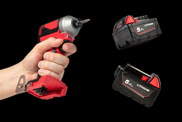 Drill in hand on a black isolated background Cordless drill or screwdriver in a male hand Removable lithium battery casts a shadow The concept of selling and using cordless tools