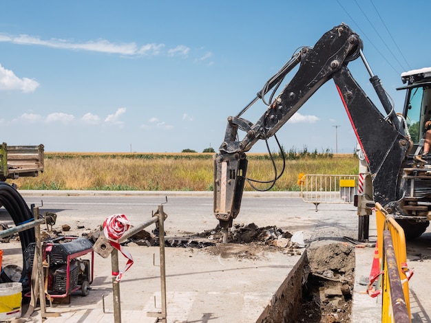 Drill series working in a trench with new water pipes in the street ground.. Public works concept.