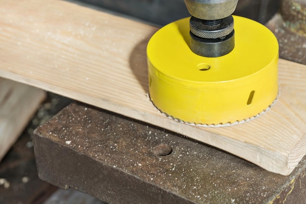 Drilling a large hole in the board with a core drill on a vertical drilling machine