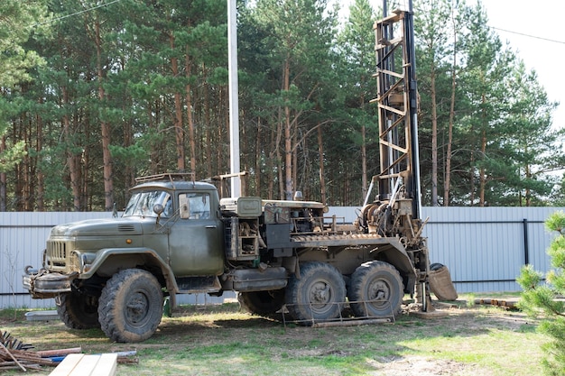 Drilling rig on zil car are drilling artesian well for water in ground Insertion of metal casing pipe into ground installation of individual drinking supply