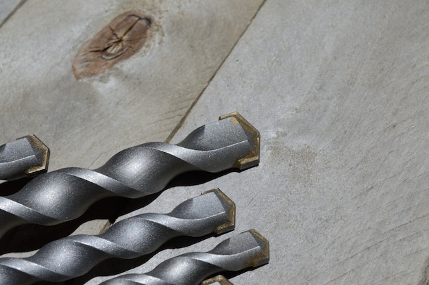 drills with carbide tip for impact drill lie on a plank wooden background. close-up.