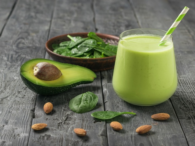 A drink of avocado, spinach and almond milk on a dark wooden table. Fitness product. Dietary sports nutrition.