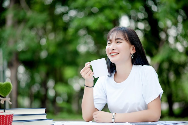 コーヒーを飲む家で一杯のコーヒーを楽しんでいる陽気な若い女性の肖像冬に熱いお茶を飲む笑顔の美しい女の子手でお茶を飲む白いマグカップからコーヒーを飲む