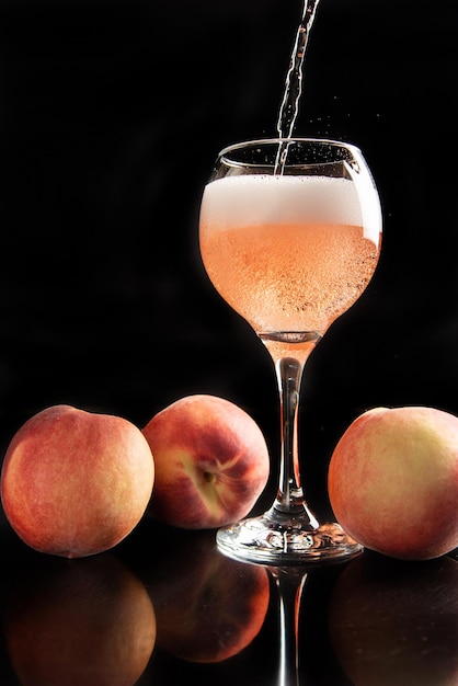 周りに桃と黒の背景の選択的な焦点とスパークリングワインを提供されているクリスタルガラスを飲む