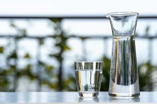 Drink de kruik van het waterglas met glas op lijst bij tuinhuis