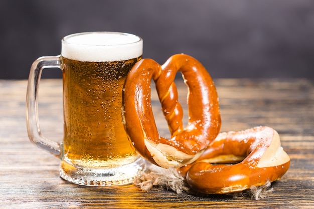 Concetto di cibo e bevande - bicchiere di birra e bagel sul tavolo di legno