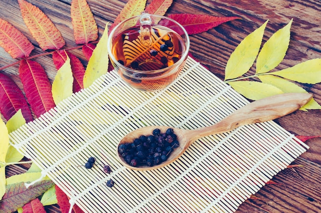 Drink From Dried Hawthorn Berries In Wooden Spoon On The Table With Colorful Autumn Leaves. 