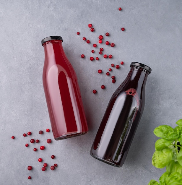 Drink from fresh cranberries and currants in bottles on a blue background with fresh herbs The concept of a healthy homemade drink with vitamins and antioxidants Top view