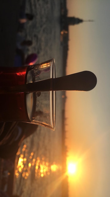 Drink in glass against sea during sunset