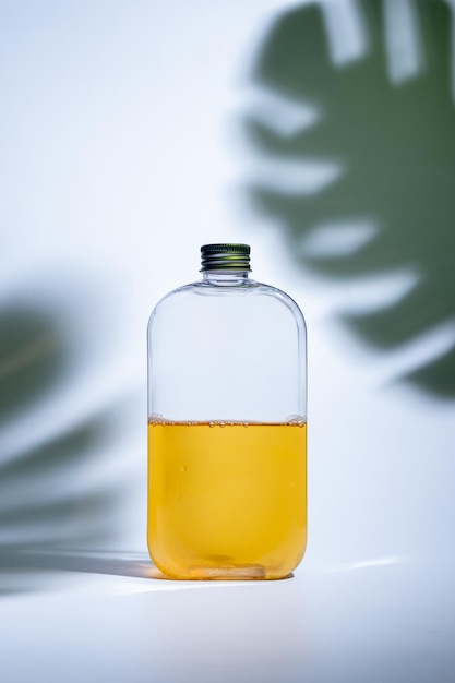 Drink in a glass bottle on white background with hard or Harsh shadows and sunlight of leaves tree branch falling on wall modern and minimal product design cold refreshment beverage