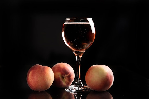 Drink glass of sparkling wine with peaches around and black background selective focus