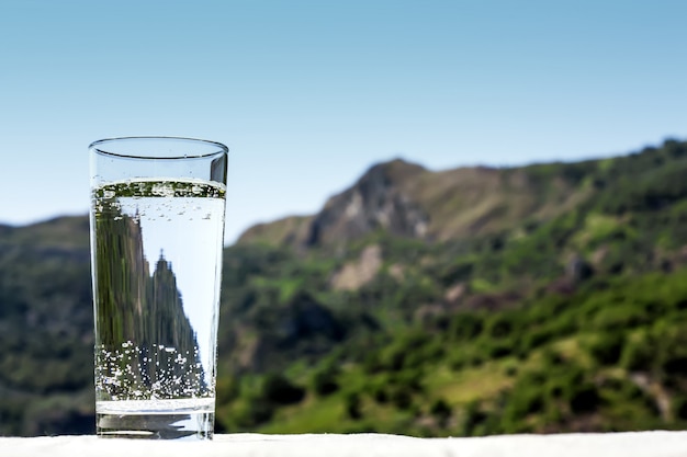 Drink glass with pouring clear water on nature