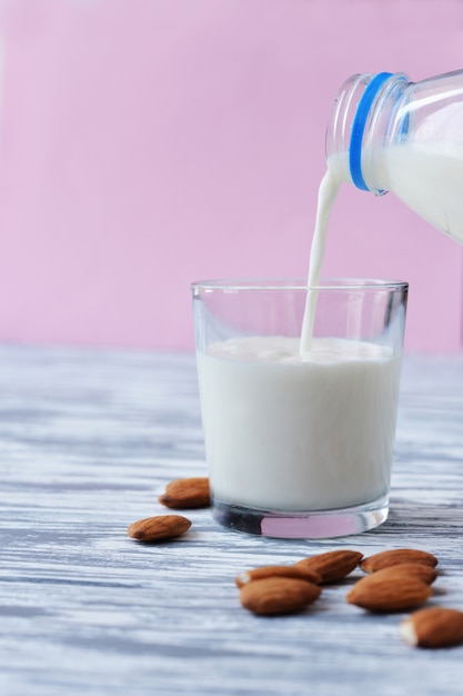 Drink milk with almonds, hand pours into a glass 