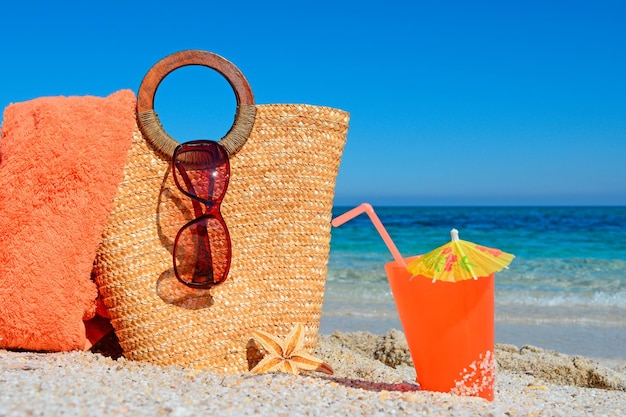 Photo drink and straw bag on the shore