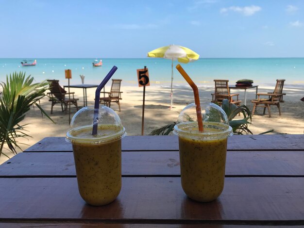 Drink on table at beach against sky