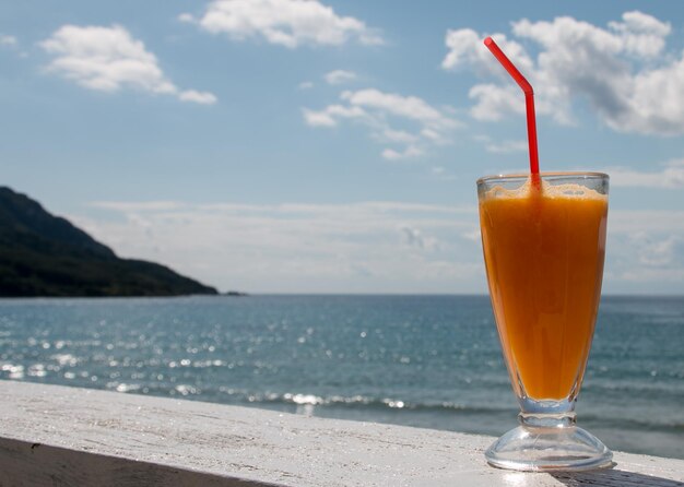 Drink on table by sea against sky