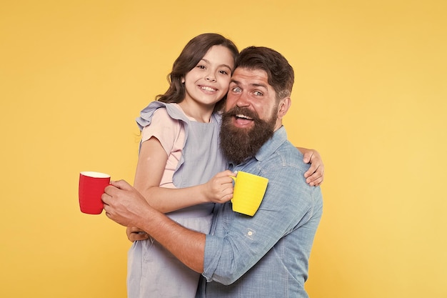 Foto bere acqua bere succo fresco concetto di colazione buongiorno bere caffè insieme bella tradizione familiare bere tè uomo barbuto e ragazza felice con tazze padre e figlia bevanda calda