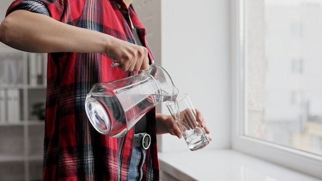 Drink water. A woman's hand pours fresh clean water from a jug into a glass. Health and beauty.