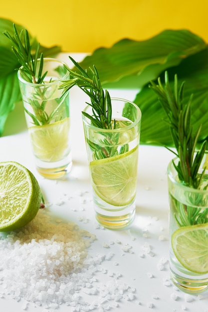 Drink with lime and rosemary on yellow background