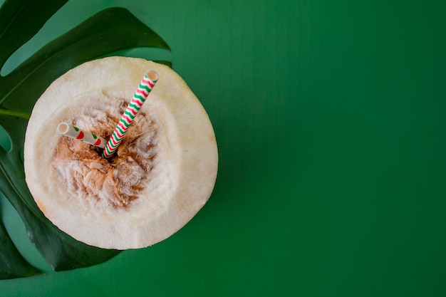 drink of young coconut with paper straws on a green background