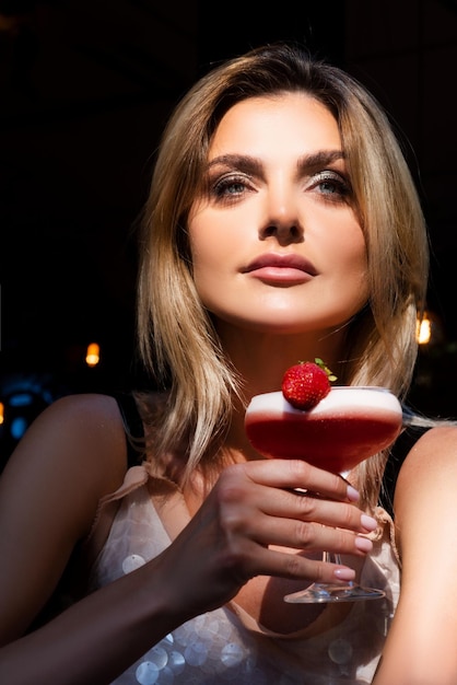 Drinken in nachtclub Sexy vrouw die een witte jurk draagt, drinkt een cocktail van Margarita met ijs Charmante dame die geniet van een gratis zomerdrankje