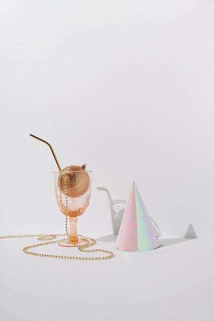 Drinkglas met goudkleurige kerstbalparels en feestmuts Minimaal begroetingsconcept