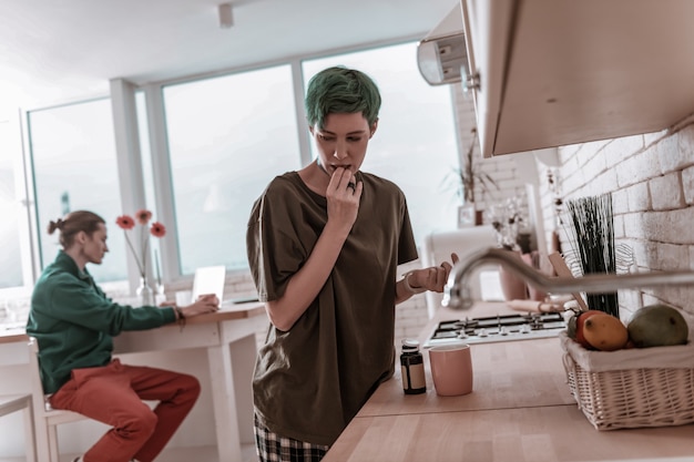 Drinking antidepressants. Green-haired woman drinking antidepressants while suffering from depression