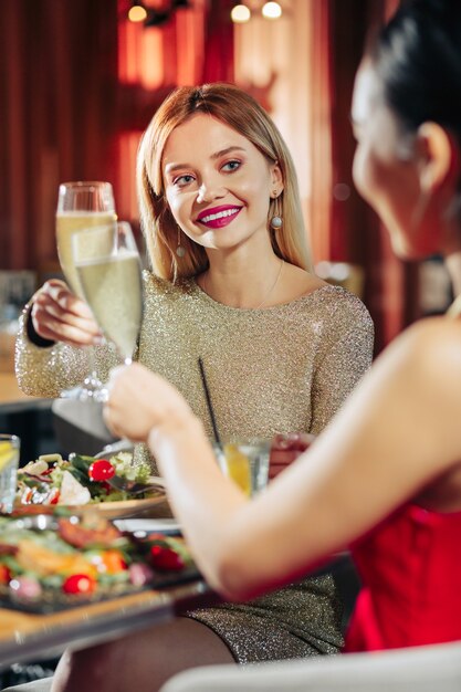 Drinking champagne Beautiful woman with nice evening makeup drinking champagne with friends