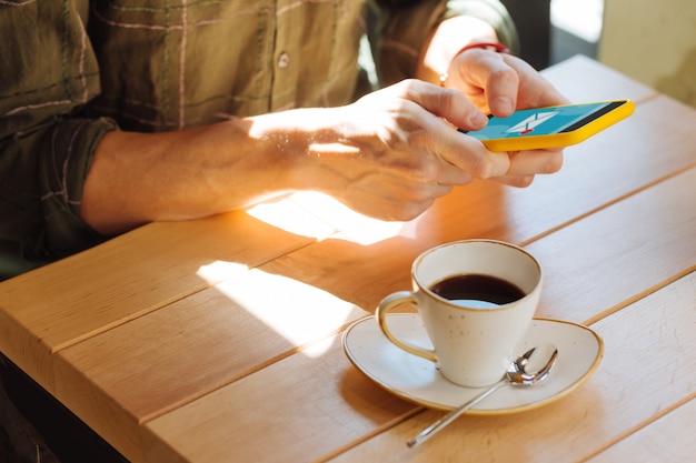 コーヒーを飲んでいる。素敵な若い男に酔っている間、半分いっぱいのコーヒーカップのクローズアップ