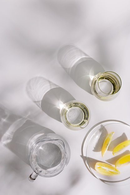 Drinking natural water in colored glass glasses and jug and plate with slices of lemon