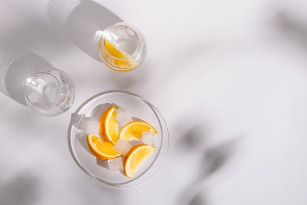 Drinking natural water and ice in beautiful glass glasses and slice of fresh orange