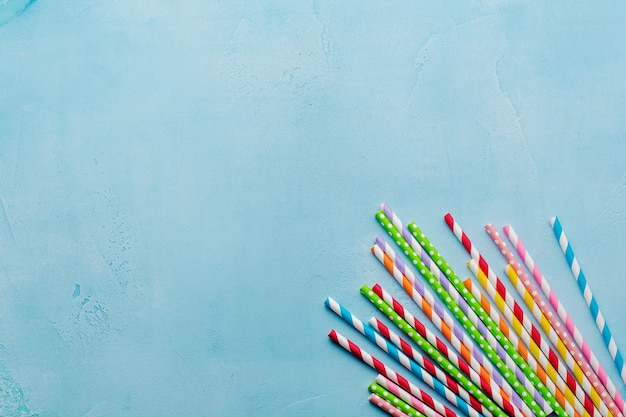 Drinking paper colorful straws for summer cocktails on light blue