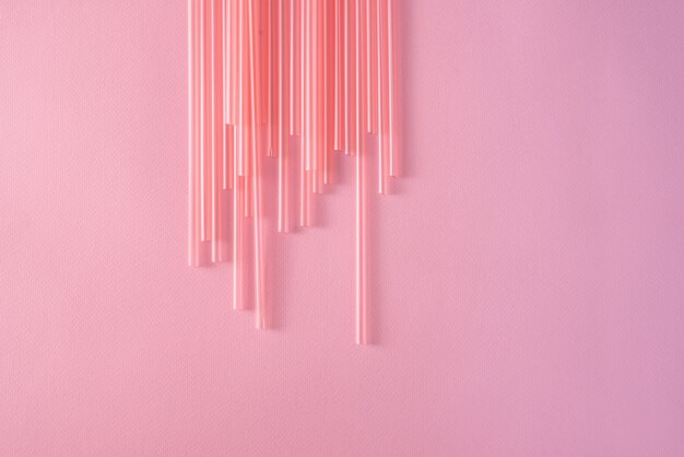 Drinking straws on bright pink background, top view