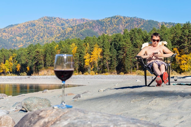 写真 暖かい秋の日にビーチでワインを飲む前景デフォーカスのガラスで休暇や旅行のコンセプト