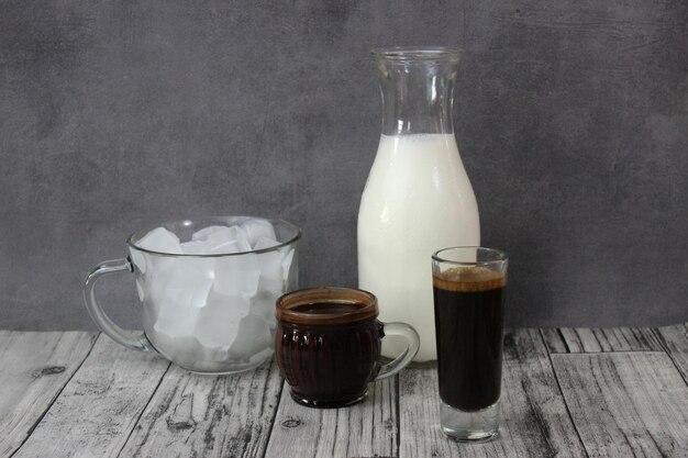 Drinks coffee and chocolate milk mochacino in glass and bottle on wood table againts grey wall