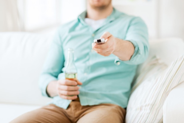 음료, 텔레비전, 여가, 그리고 사람들의 개념 - TV 채널을 바꾸고 집에서 맥주를 마시는 남자