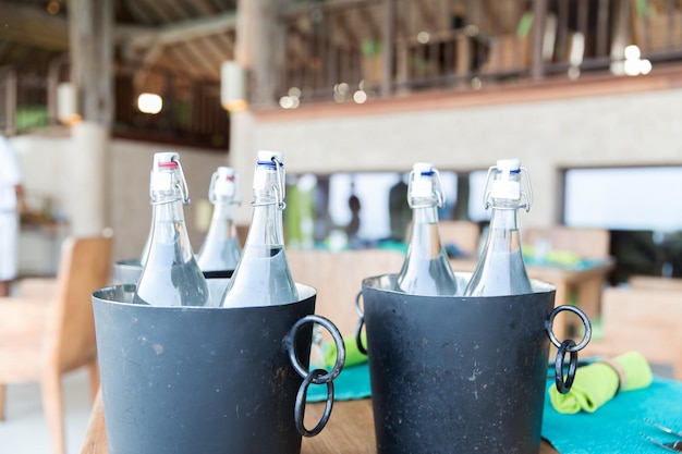 drinks, thirst, refreshment and summer resort concept - bottles of water in ice bucket at hotel restaurant