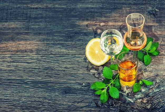 木製の背景に氷、レモン、ミントの葉と飲み物。ヴィンテージスタイルのトーンの写真