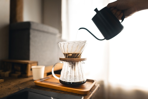 Caffè a goccia, barista che versa acqua sul caffè macinato con filtro, preparazione del caffè