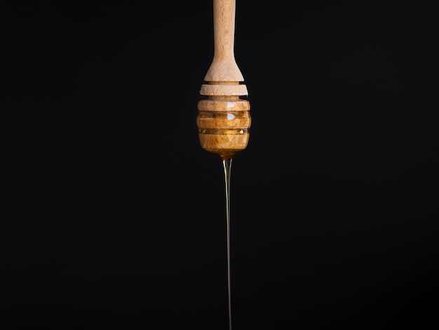 Photo dripping honey on black background