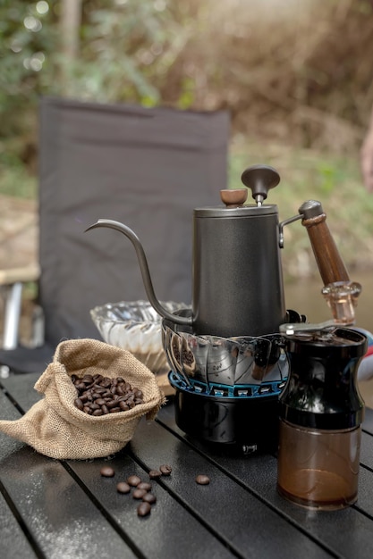 Dripping hot coffee and camping near river at nature park. Outdoor activity and relax on holiday.