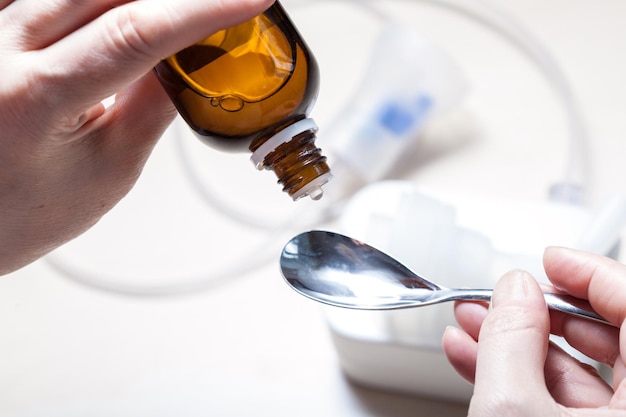 Dripping medicine from glass bottle into spoon