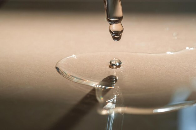 A Dripping Pipette of cosmetic gel on a beige background