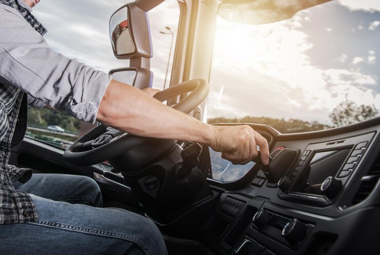 Photo driver adjusting controls while operating a large truck during sunset on the highway