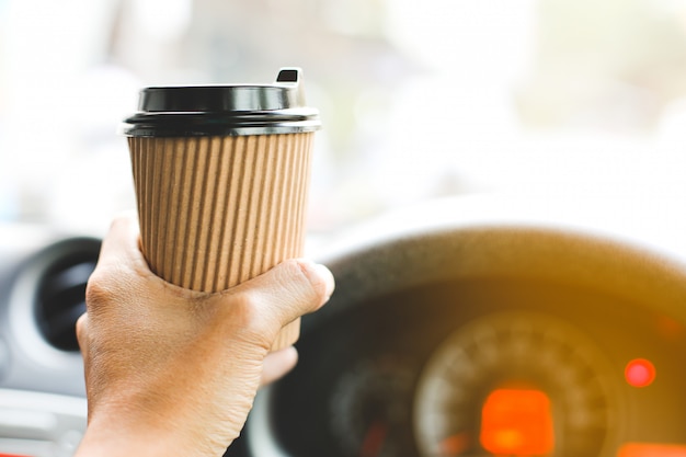 運転手が車の中でコーヒーを飲みます。