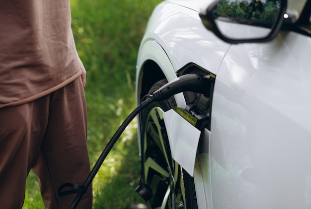 The driver of the electric car inserts the electrical connector\
to charge the batteries