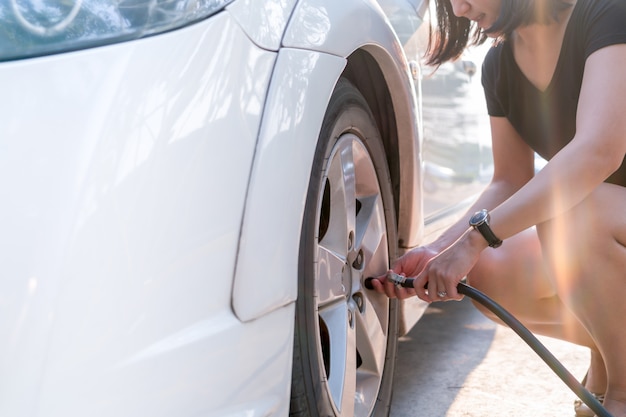 Driver filling air into a car tire, tire inflation