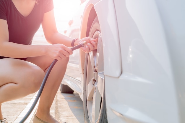 Driver filling air into a car tire, tire inflation