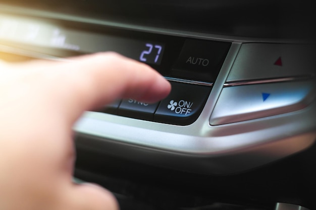 The driver hand is pressing the onoff button of the car air conditioner in the car