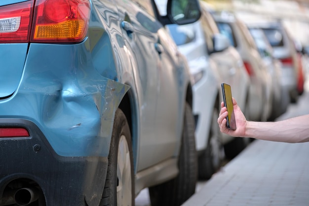 Le mani del conducente scattano foto sulla fotocamera del telefono cellulare dopo la collisione del veicolo sul lato della strada per il servizio di emergenza dopo un incidente d'auto concetto di sicurezza e assicurazione stradale